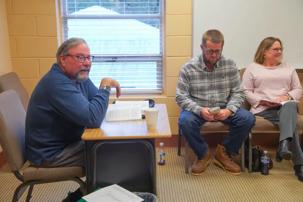 Sunday School teacher sits at desk in front of class