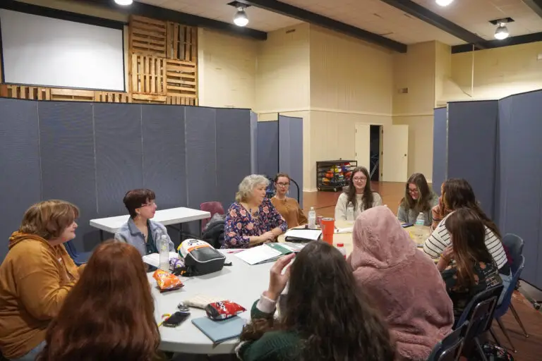 Teenage girls sit around tables for Sunday School