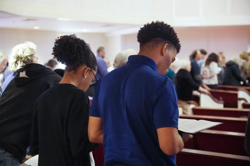 Students standing holding open bible during worship service