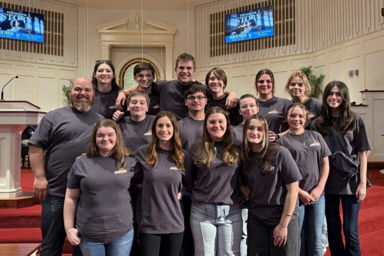 Dalraida students pose in their gray Amplify Weekend shirts on the steps of the worship center stage